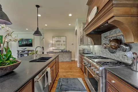 a large kitchen with stainless steel appliances granite countertop wooden floors and a view of living room