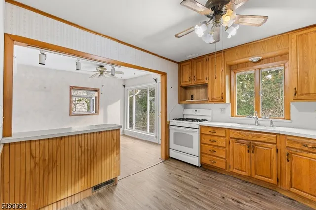 a large kitchen with a stove a sink dishwasher and a refrigerator with wooden floor