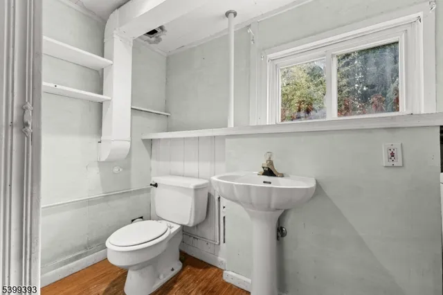 a bathroom with a sink mirror toilet and next to a window