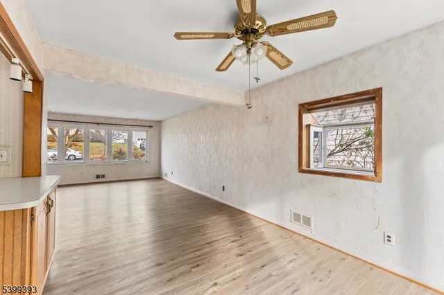 a view of an empty room with a window and wooden floor