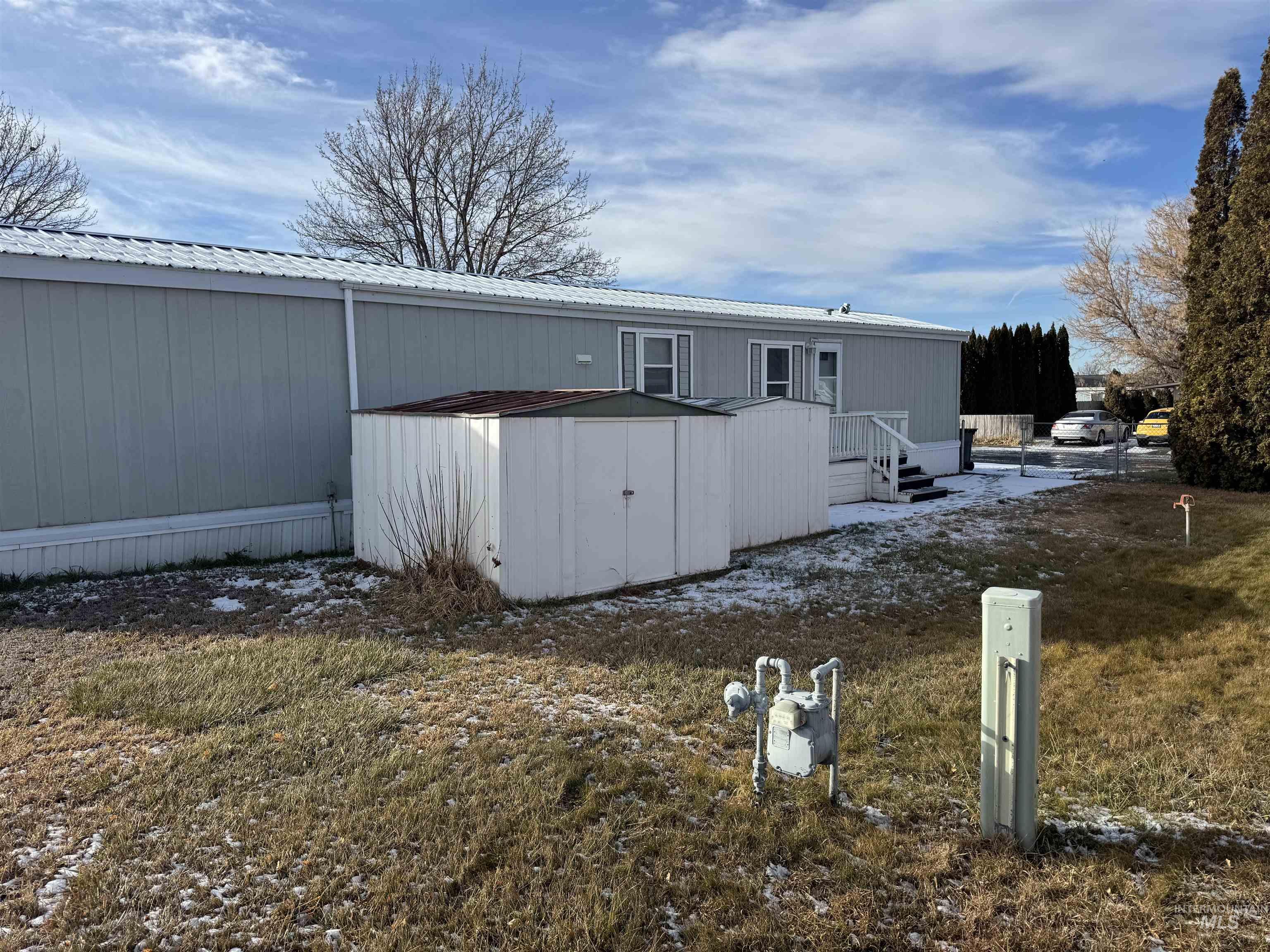 198 South Hills Road, Unit 83 Twin Falls, ID 83301 - Photo 2 of 21 View of property exterior featuring a metal roof, a yard, and a storage shed