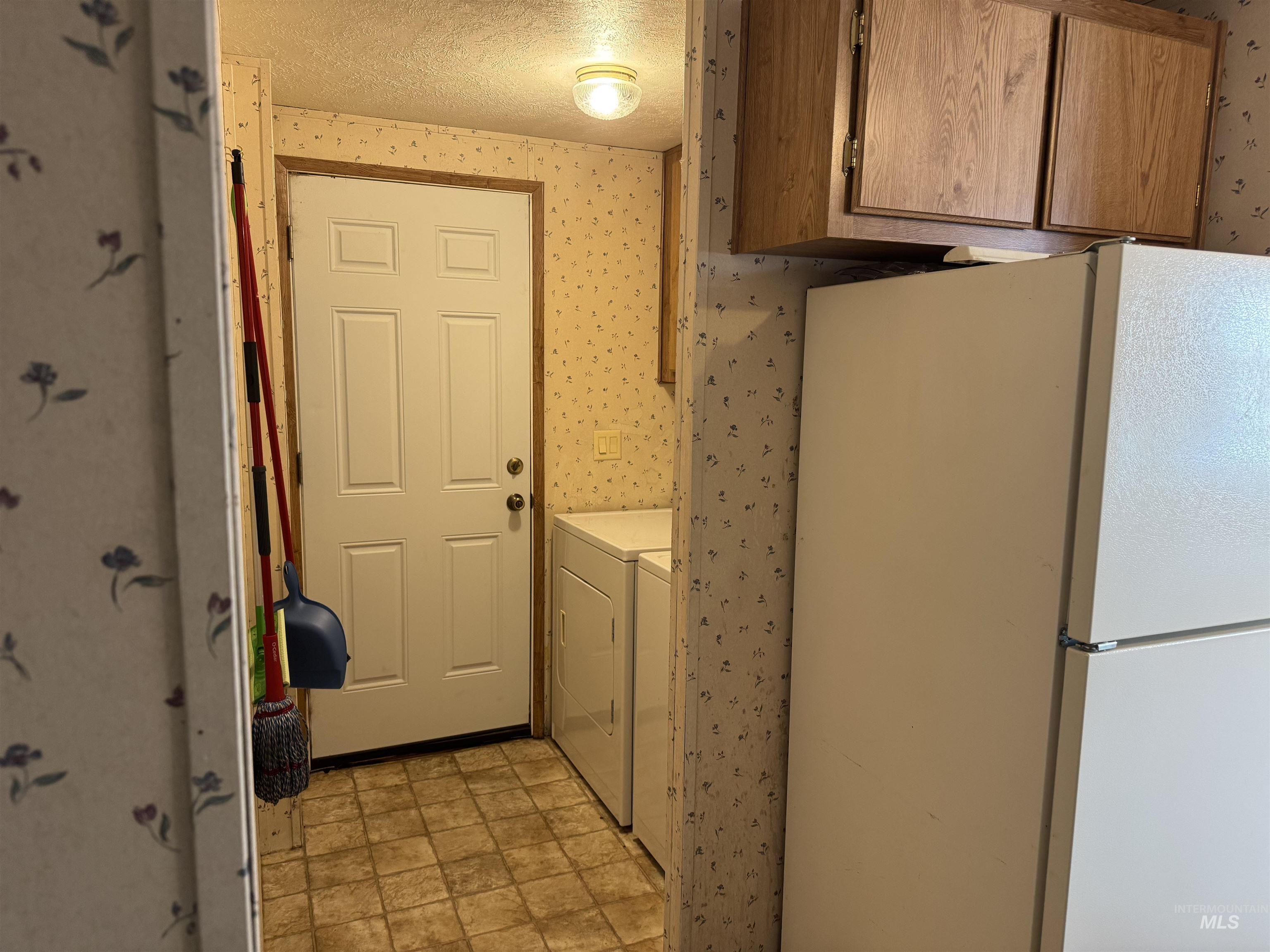 198 South Hills Road, Unit 83 Twin Falls, ID 83301 - Photo 21 of 21 Laundry room featuring wallpapered walls, a textured ceiling, independent washer and dryer, and stone finish floors