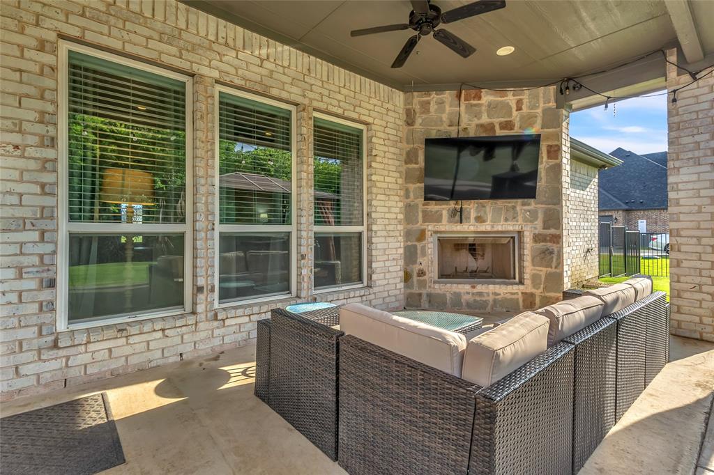 1014 Rennard Street Caddo Mills, TX 75135 - Photo 5 of 39 Covered outdoor patio featuring a stone-clad fireplace, integrated television, and a ceiling fan
