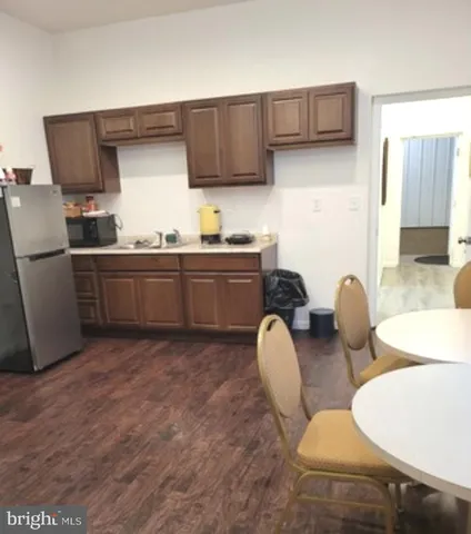 a kitchen with stainless steel appliances granite countertop a stove a sink a refrigerator white cabinets and wooden floor