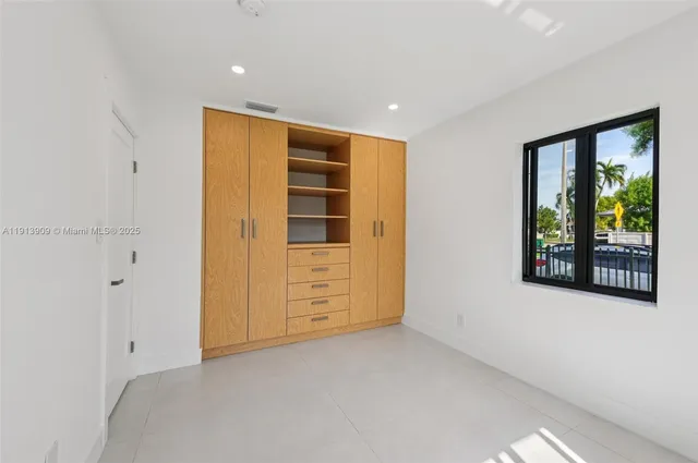 a view of an empty room with window and cabinet