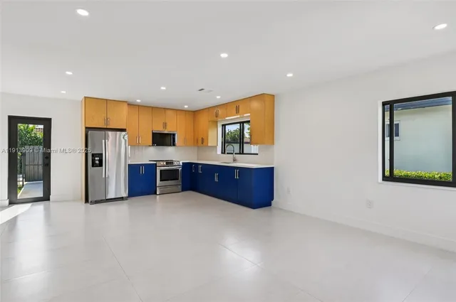 a large kitchen with stainless steel appliances a large counter top a stove and a refrigerator