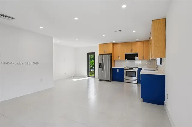 a large kitchen with stainless steel appliances a large counter top a stove and a refrigerator