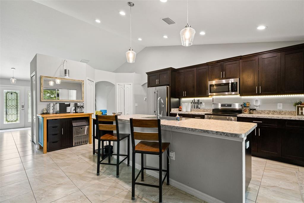 12015 Phoenix Avenue Weeki Wachee, FL 34614 - Photo 12 of 39 a kitchen with stainless steel appliances kitchen island granite countertop a stove top oven a sink dishwasher a dining table and chairs