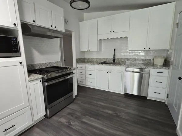 a kitchen with granite countertop white cabinets and white appliances
