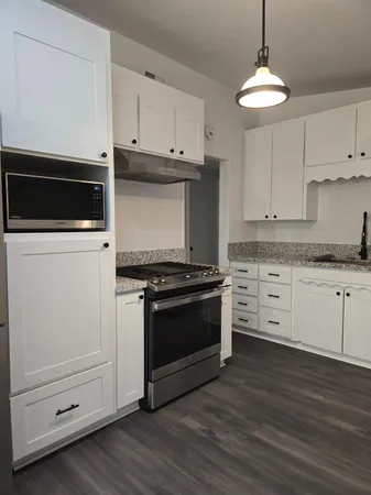 a kitchen with stainless steel appliances white cabinets and a stove a oven with wooden floors
