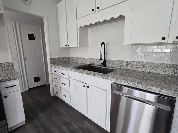 a kitchen with granite countertop white cabinets and a sink