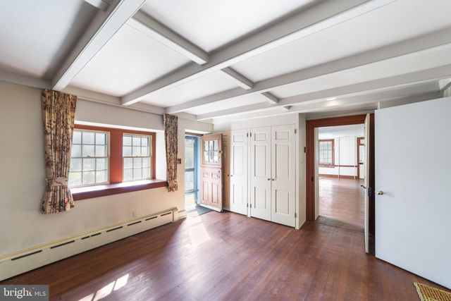 a view of an empty room with wooden floor fireplace and a window