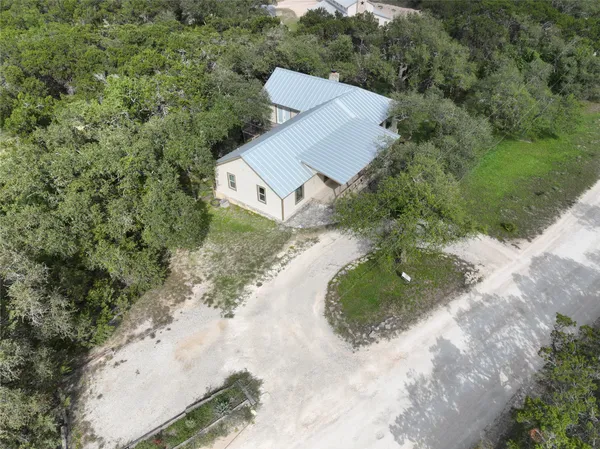 an aerial view of a house with a yard and trees all around