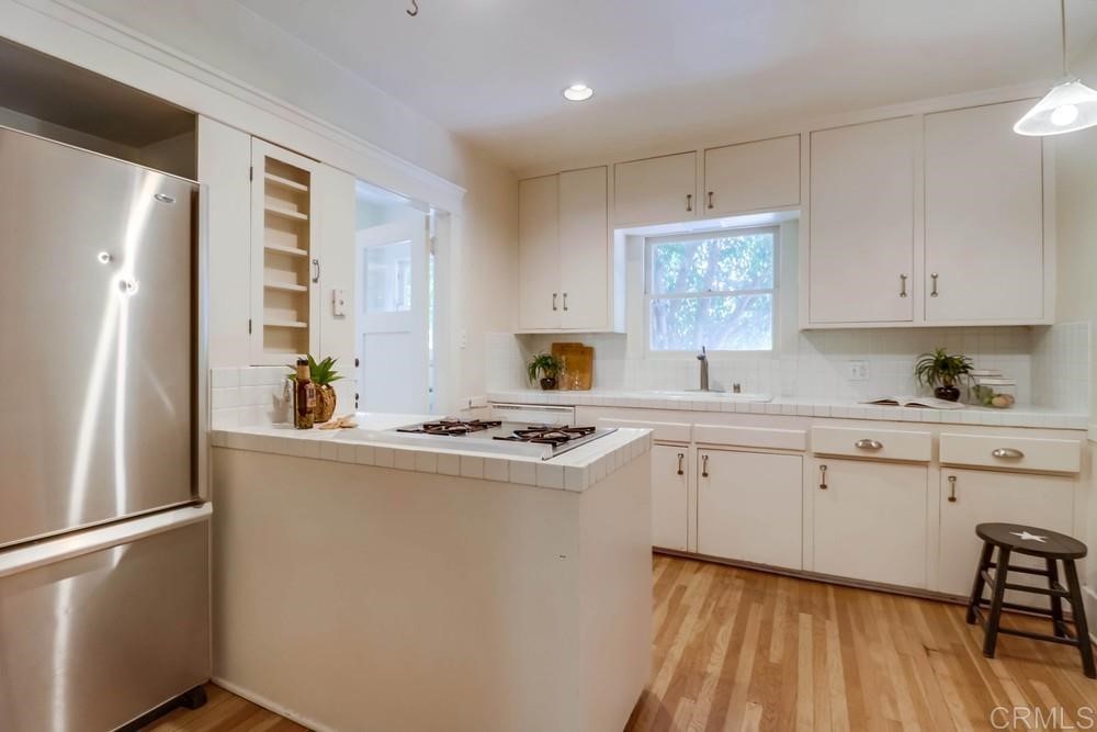 1944 Granada Avenue San Diego, CA 92102 - Photo 28 of 65 a kitchen with stainless steel appliances granite countertop a stove a refrigerator a sink dishwasher and white countertops with wooden floor