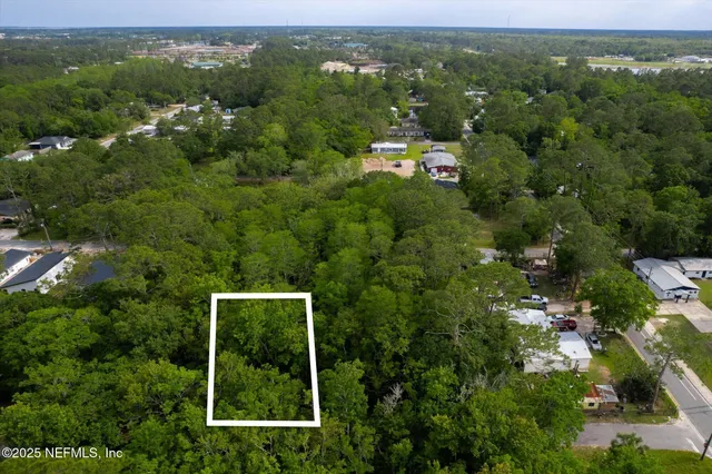 an aerial view of residential houses with outdoor space and trees