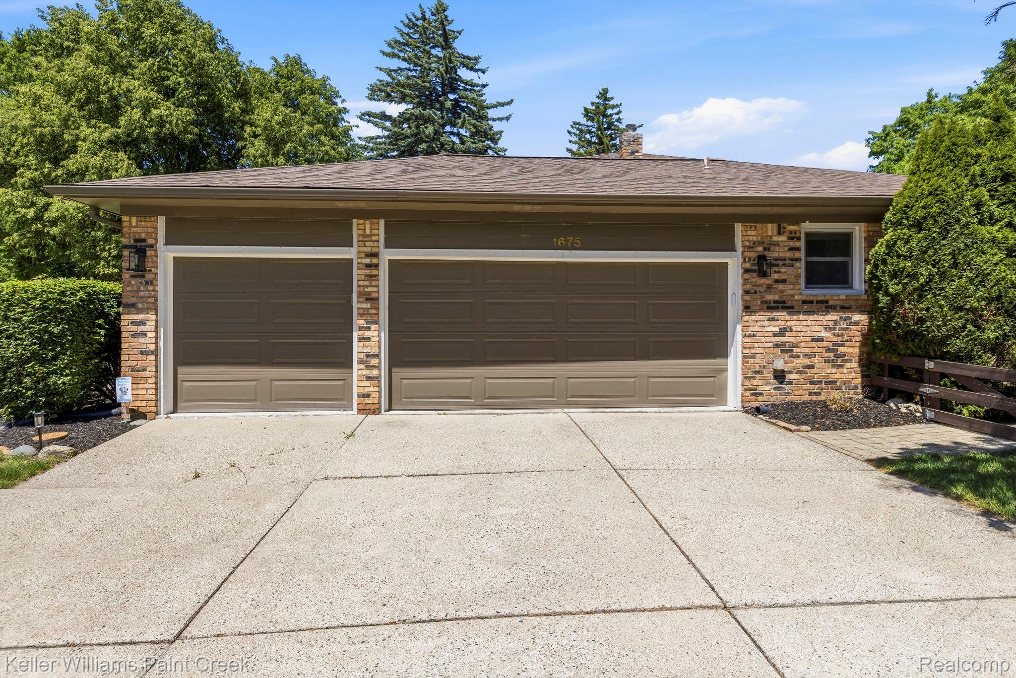 1675 North Kilburn Road Rochester, MI 48306 - Photo 4 of 48 Two-car garage featuring brown doors, brick accents, and a concrete driveway