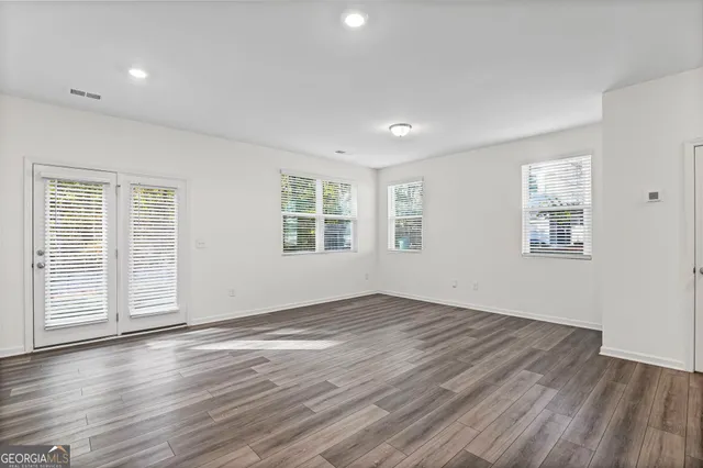 an empty room with wooden floor and windows
