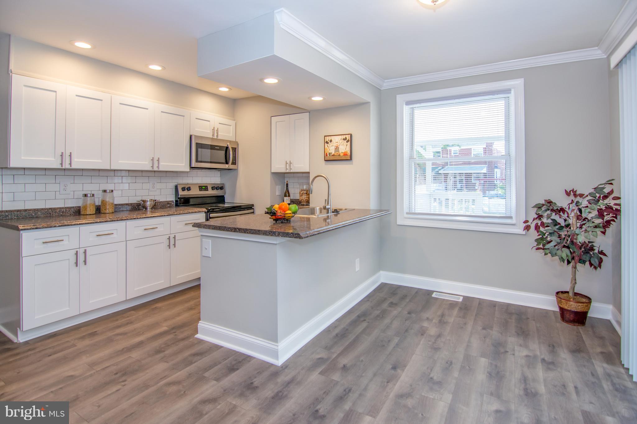2056 Jasmine Road Dundalk, MD 21222 - Photo 1 of 30 a open kitchen with white cabinets and wooden floor