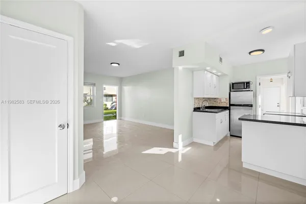 a view of a kitchen with refrigerator and white cabinets