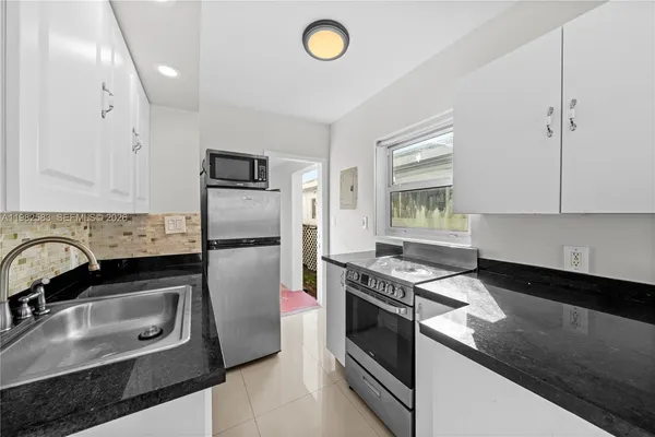 a kitchen with granite countertop a stove sink and refrigerator