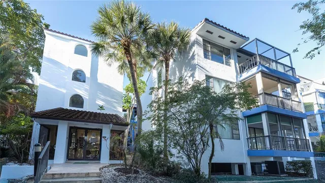 a front view of a building with a garden and trees