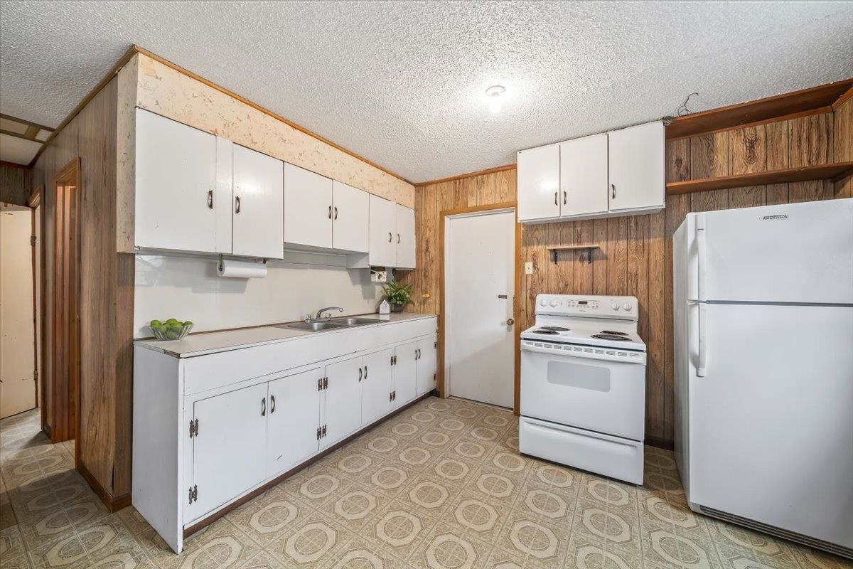 2972 Russell Bond Road Millington, TN 38053 - Photo 28 of 38 Kitchen featuring white cabinets, white appliances, wood walls, light countertops, and a textured ceiling