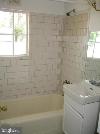 11705 Idlewood Road Silver Spring, MD 20906 - Photo 7 of 10 a white bath tub sitting next to a white sink and a shower