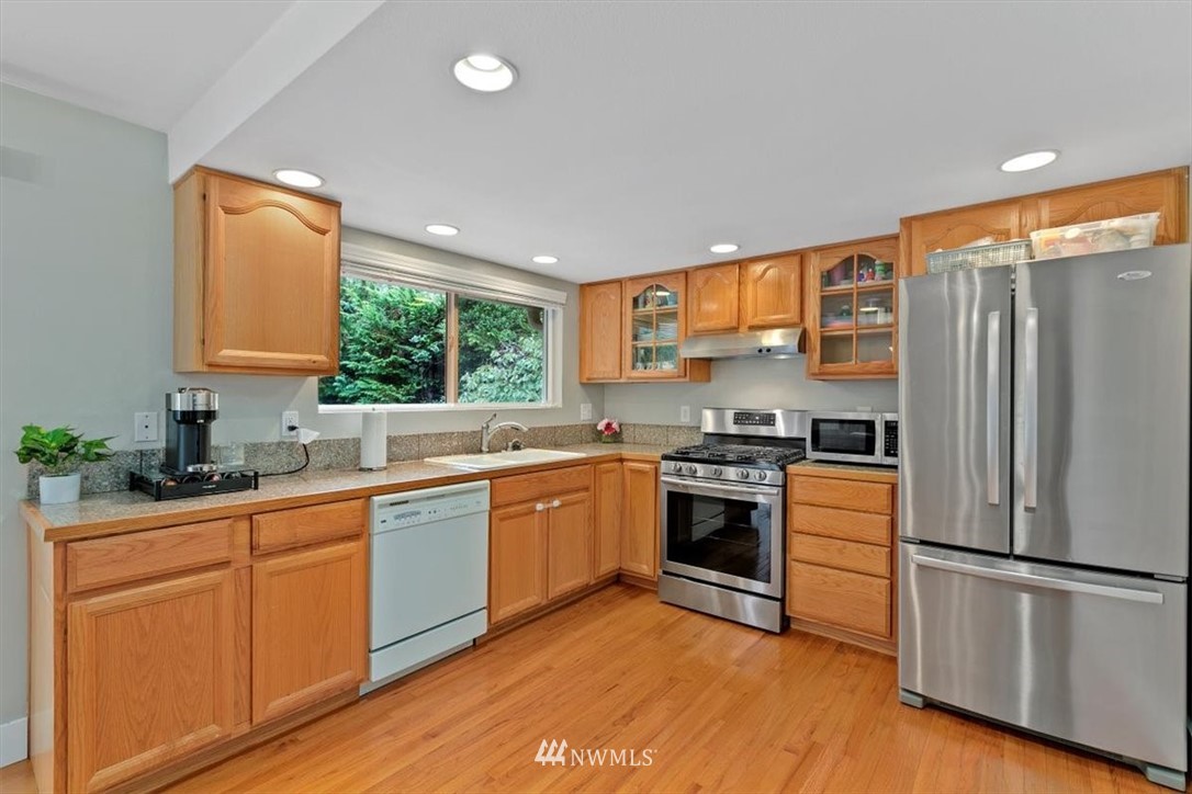 12656 177th Place Southeast Renton, WA 98059 - Photo 7 of 27 a kitchen with stainless steel appliances granite countertop a refrigerator a sink dishwasher a stove with wooden cabinets and wooden floor