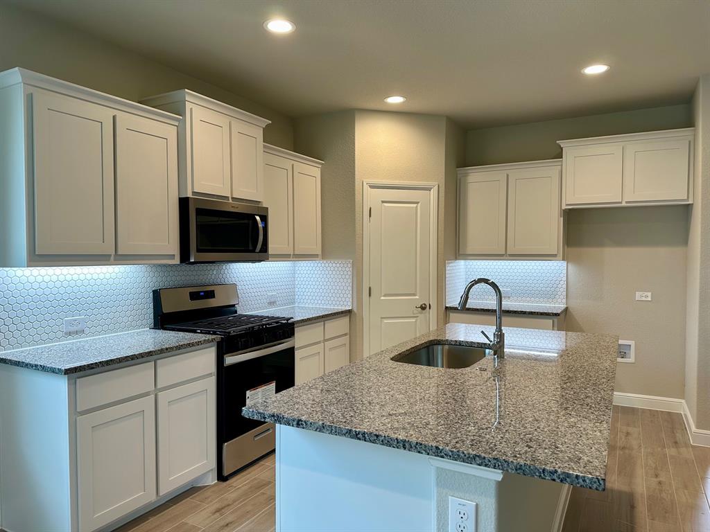 11505 Adare Drive Haslet, TX 76052 - Photo 5 of 17 a kitchen with granite countertop a sink and white cabinets