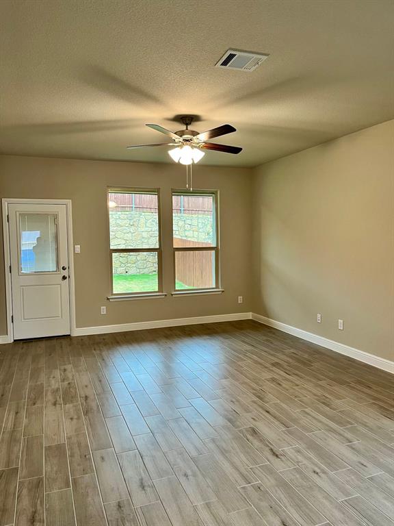11505 Adare Drive Haslet, TX 76052 - Photo 8 of 17 an empty room with wooden floor chandelier fan and windows