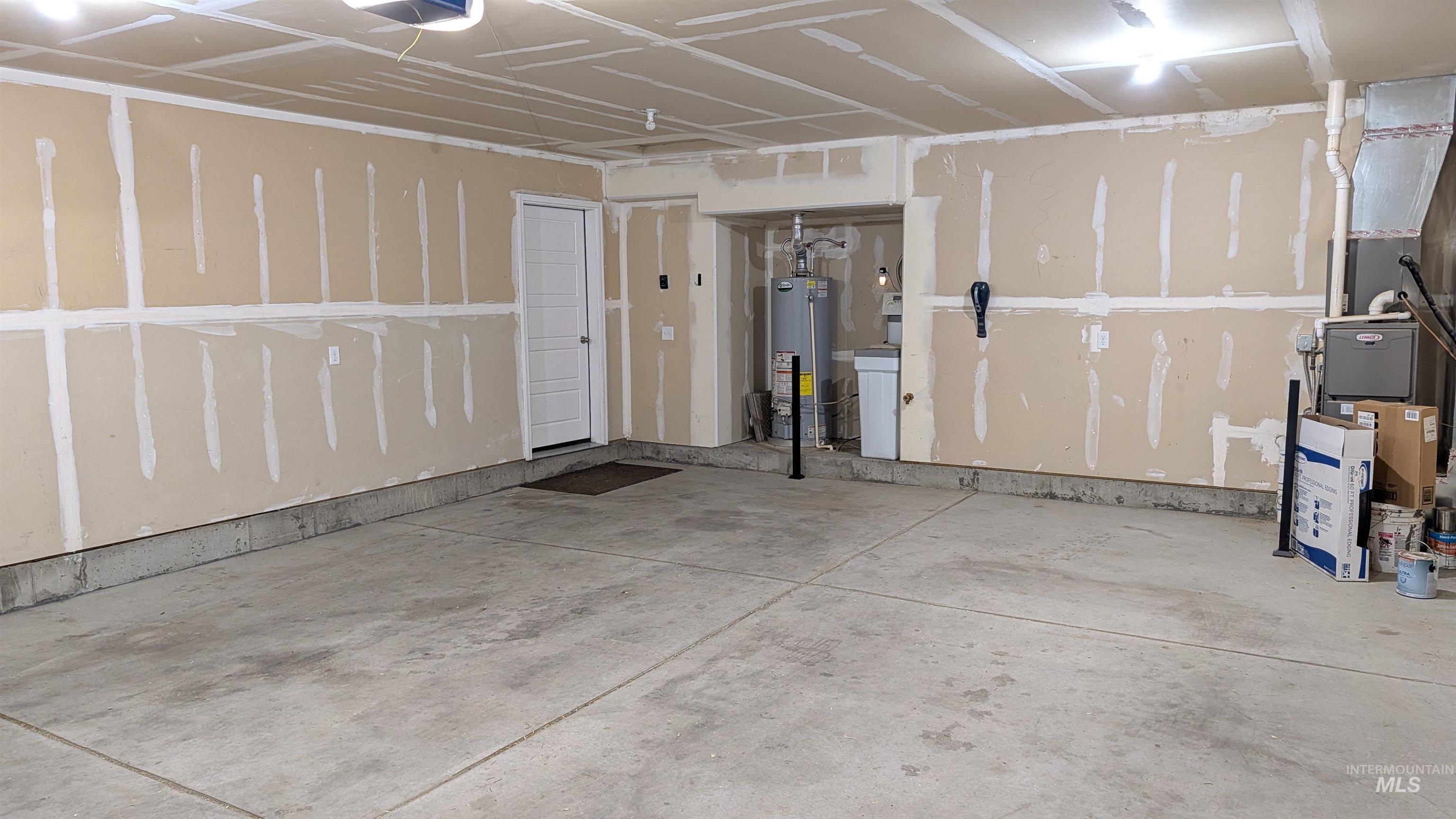 622 Lochsa Loop Heyburn, ID 83336 - Photo 5 of 17 Spacious garage featuring a concrete floor, light-colored walls with visible drywall mudding, overhead lighting, and a white interior door