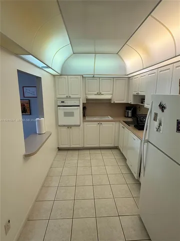 a kitchen with white cabinets a counter top space and appliances