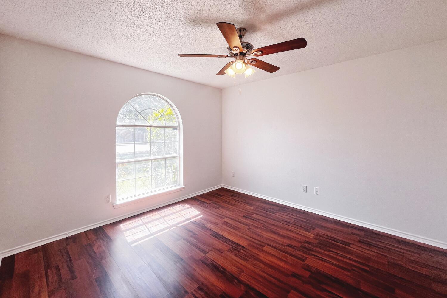 6114 10th Street Lubbock, TX 79416 - Photo 15 of 24 an empty room with wooden floor fan and windows