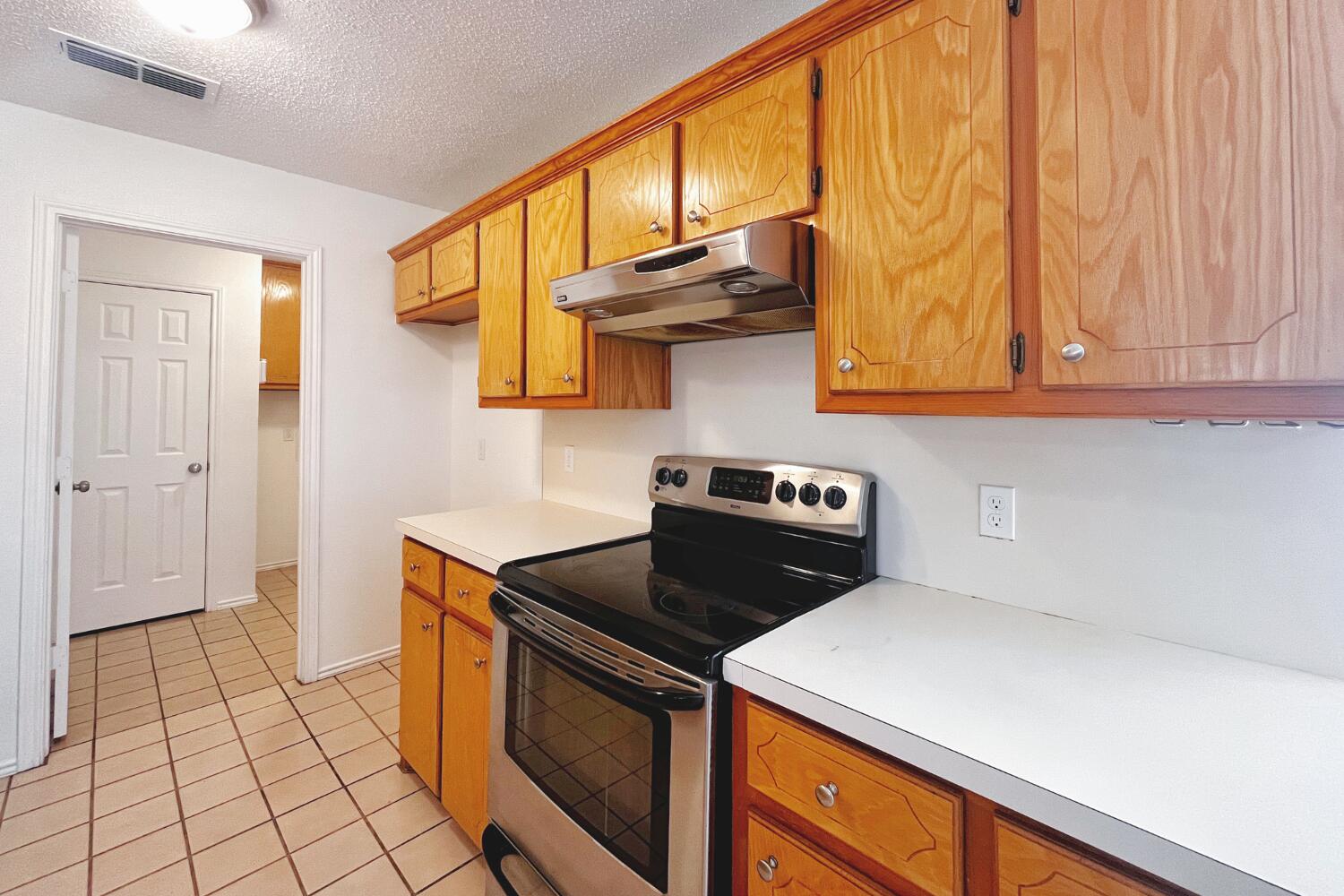 6114 10th Street Lubbock, TX 79416 - Photo 9 of 24 a kitchen with stainless steel appliances a stove a sink and cabinets