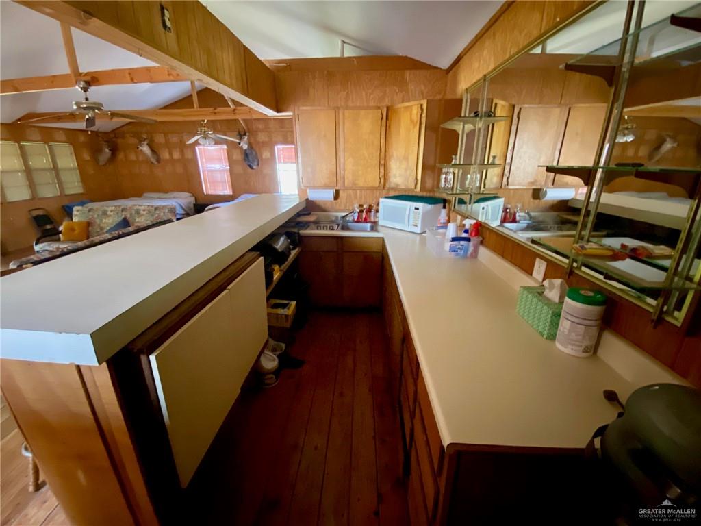 Wood-paneled interior featuring a vaulted ceiling with exposed beams, wood-finish flooring, and built-in wood cabinetry with light-colored countertops