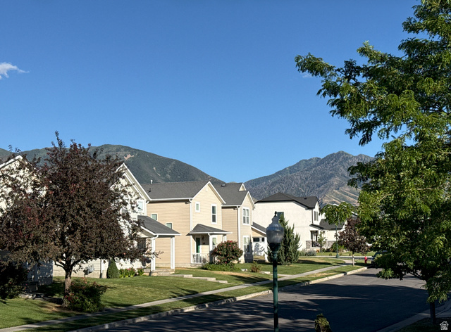 1705 80 East Tooele, UT 84074 - Photo 22 of 22 Mountain backdrop with residential street featuring manicured lawns, mature trees, and street lighting