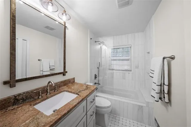 a bathroom with a granite countertop sink toilet and shower