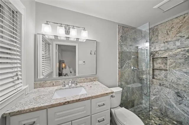 a bathroom with a granite countertop sink mirror and toilet