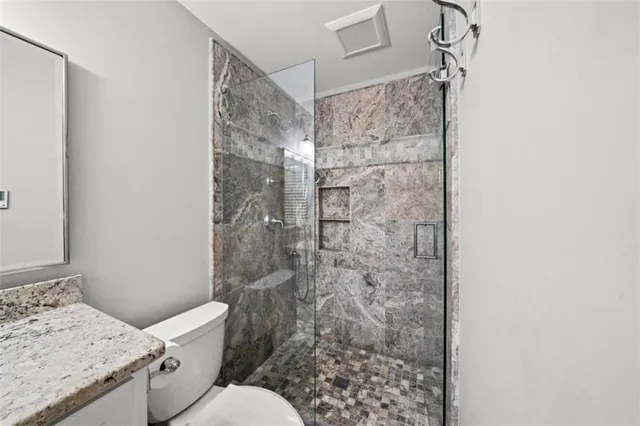 a bathroom with a granite countertop toilet a sink and shower