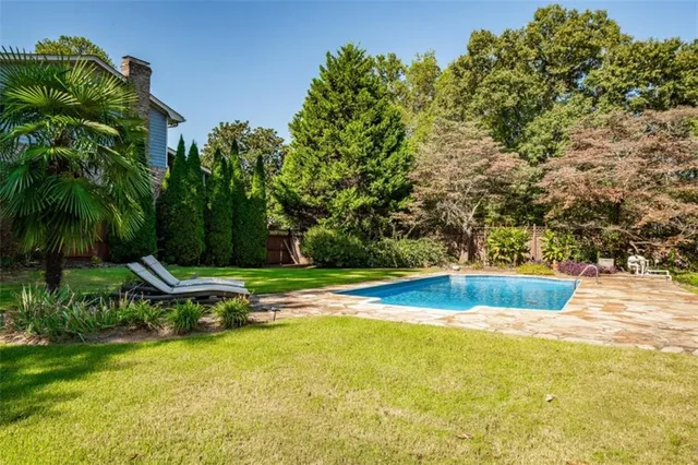 a view of a swimming pool with a yard and trees
