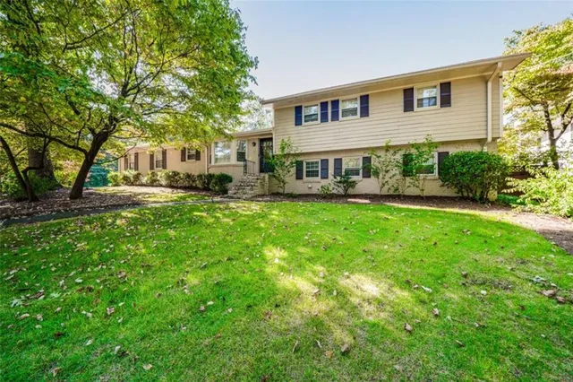 a front view of a house with a yard and trees