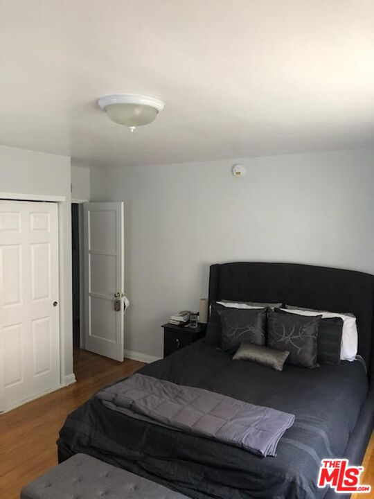 127 North Clark Drive Beverly Hills, CA 90211 - Photo 5 of 9 a bedroom with a bed and wooden floor
