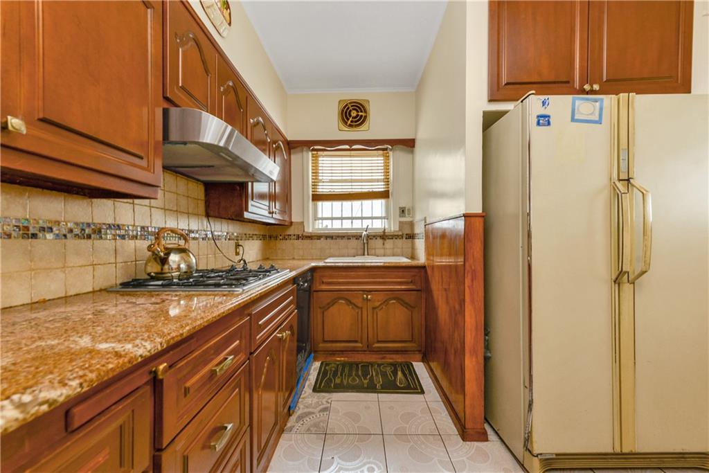 4203 Avenue I Brooklyn, NY 11210 - Photo 7 of 19 a kitchen with a refrigerator a sink and wooden cabinets