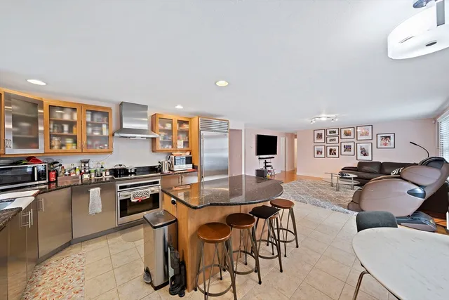 a dining hall with stainless steel appliances granite countertop a stove a sink a dining table and chairs with wooden floor