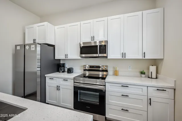 a kitchen with stainless steel appliances white cabinets and a refrigerator