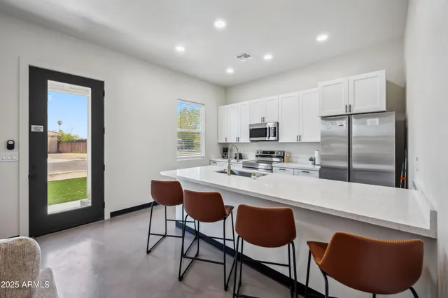 a kitchen with stainless steel appliances granite countertop a sink a stove a refrigerator a microwave a dining table and chairs with wooden floor