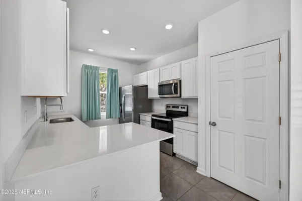 a large white kitchen with a refrigerator a stove top oven a sink and dishwasher