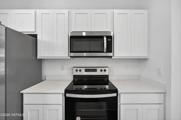 a kitchen with stainless steel appliances granite countertop white cabinets a stove top oven