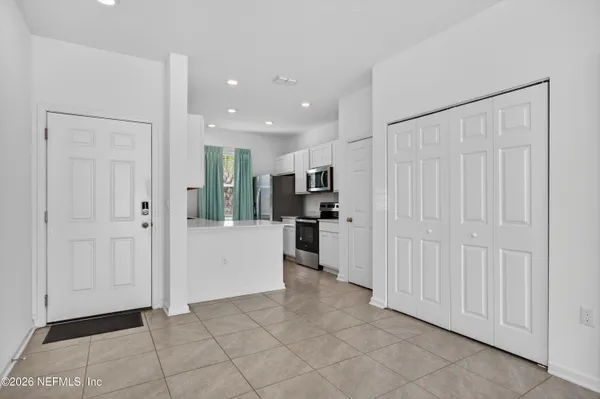 a view of a kitchen with refrigerator and white cabinets