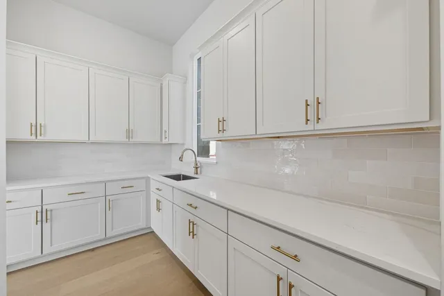 a kitchen with white cabinets and sink